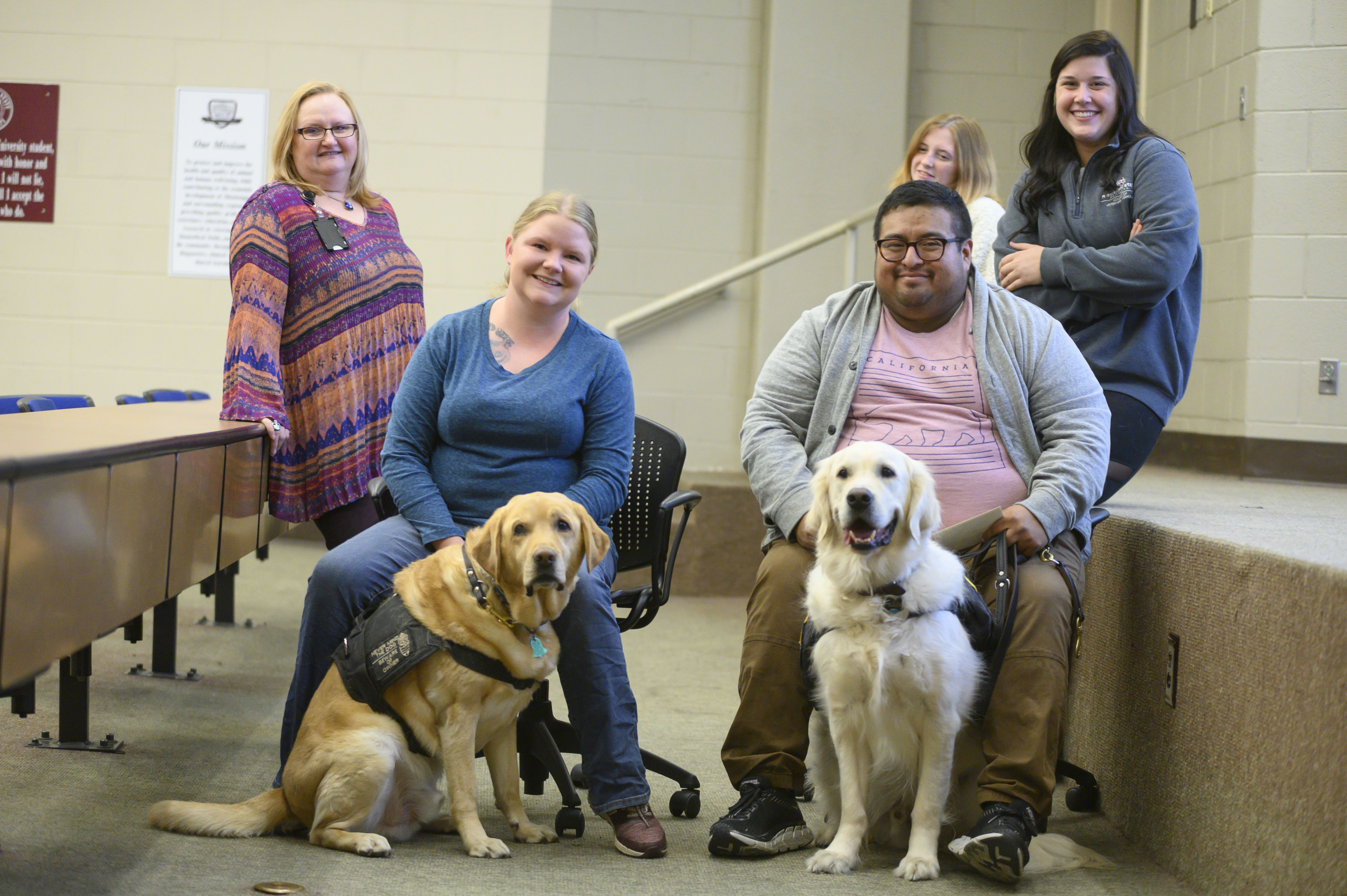 Four people pose with two service dogs